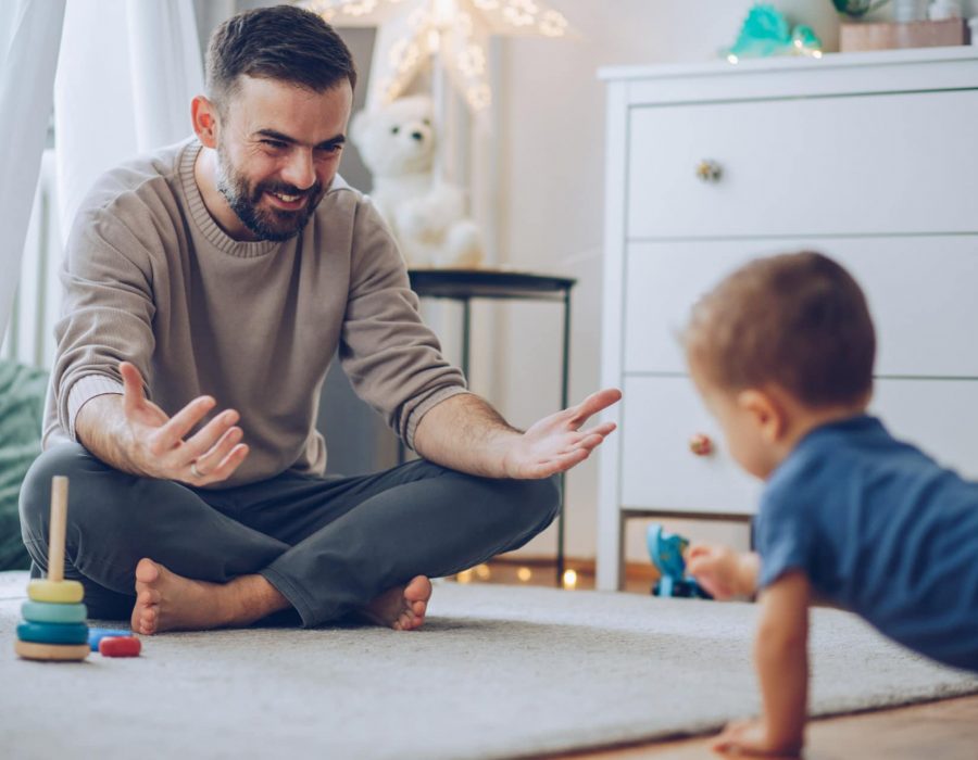 Little baby crawling on floor, father encourage it, and call it to come to him
